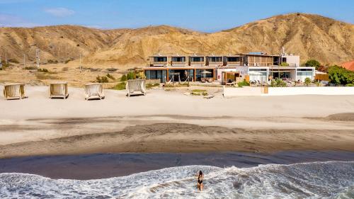 a person standing on the beach in front of a house at Norte Suites Boutique in Los Órganos