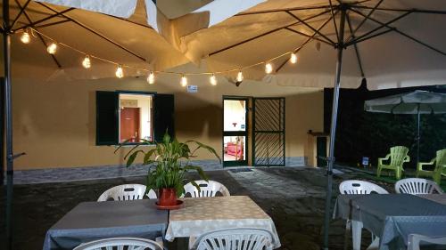 a patio with tables and white chairs and umbrellas at Il Gelso in Trivigno