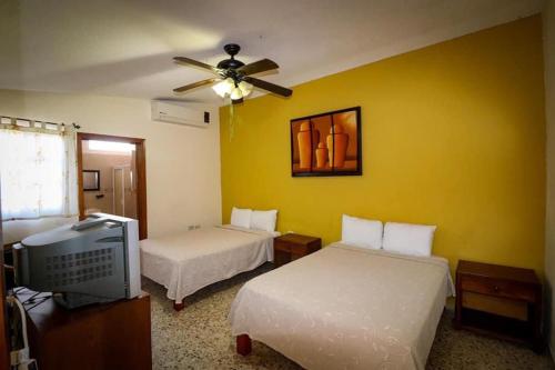 1 dormitorio con 2 camas y TV. en Hotel Franco, en El Fuerte