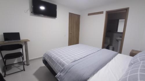 a bedroom with a bed and a desk and a television at Hotel Andina Blue in Funza