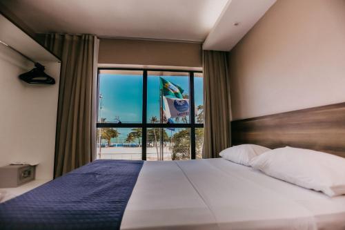 a bedroom with a bed and a large window at Pajuçara Praia Hotel in Maceió