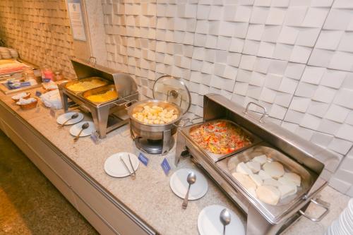 a kitchen counter with some food and plates of food at Pajuçara Praia Hotel in Maceió