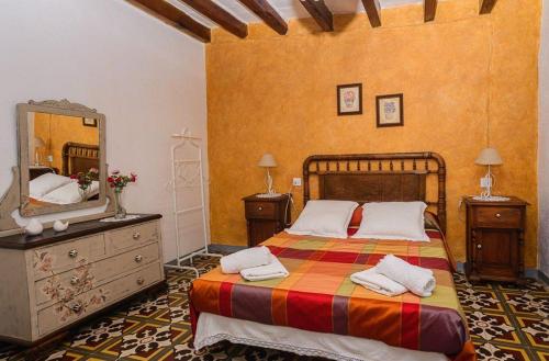 a bedroom with a bed with a dresser and a mirror at Habitour - Casa la Cenia in Cervera del Maestre