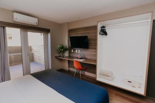 a bedroom with a bed and a desk with a television at Pajuçara Praia Hotel in Maceió