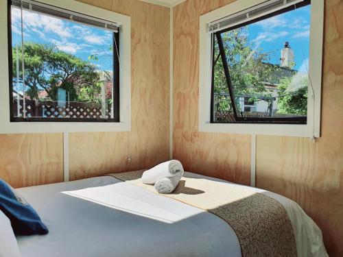 Un dormitorio con dos ventanas y una cama con un animal de peluche. en Dunedin Luxurious Retreat Cabin en Dunedin