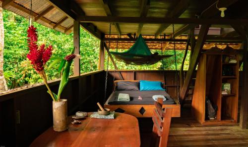 a room with a table and a hammock in a house at Dolphin Quest Jungle Lodge in Piedras Blancas
