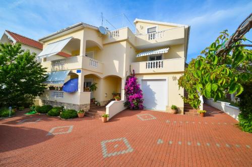 a large white house with a red brick driveway at Apartments Veronika in Zadar