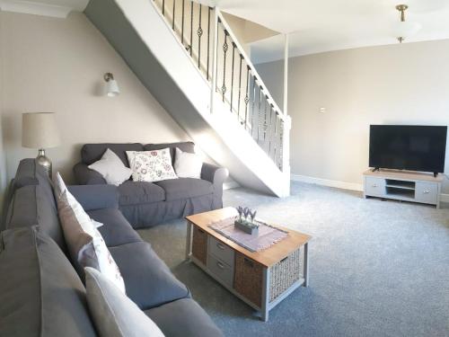 uma sala de estar com um sofá e uma televisão em Cosy 3 bedroom residential house, private garden, 30 minutes from Alton Towers, 5 minute walk to Trentham Gardens. em Stoke-on-Trent