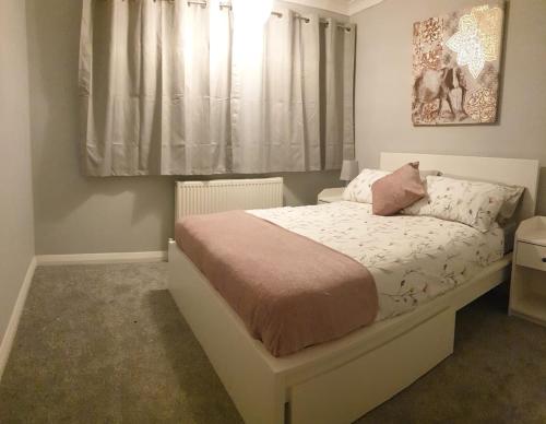 a bedroom with a white bed with a window at Cosy 3 bedroom residential house, private garden, 30 minutes from Alton Towers, 5 minute walk to Trentham Gardens. in Stoke on Trent