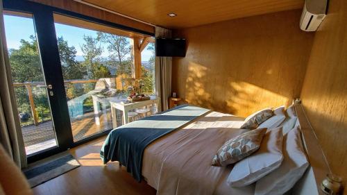 a bedroom with a bed and a large window at Horizonte Monte Verde in Mondim de Basto