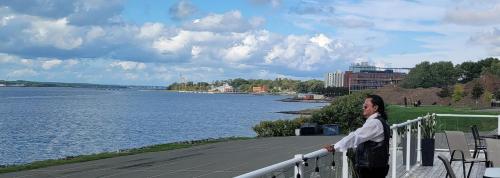 un hombre parado en una barandilla junto a un cuerpo de agua en Harbourview Inn and Suites en Sydney