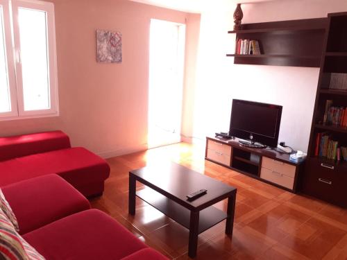 - un salon avec un canapé rouge et une télévision dans l'établissement SX6 Ático con terraza en centro histórico Pontevedra, à Pontevedra