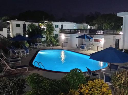ein Pool mit blauen Sonnenschirmen in der Nacht in der Unterkunft 126 Friendship, Rockley Golf Club in Bridgetown