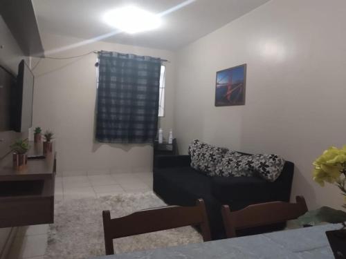 a living room with a black couch and a window at Recanto chalenger in Campos dos Goytacazes