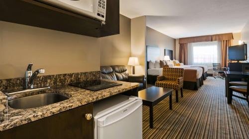 ein Hotelzimmer mit einer Küche und einem Schlafzimmer in der Unterkunft Best Western Plus Peace River Hotel & Suites in Peace River