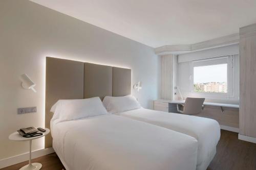 sypialnia z dużym białym łóżkiem i oknem w obiekcie NH Barajas Airport w Madrycie
