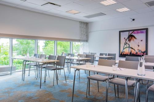 a dining room with tables and chairs and windows at Radisson Blu Hotel Uppsala in Uppsala