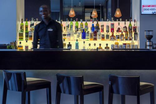 a man standing behind a bar with three chairs at Radisson Blu Hotel, Nairobi Upper Hill in Nairobi