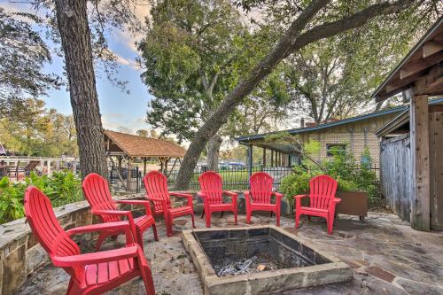 a group of red chairs sitting around a fire pit at Guadalupe River Paradise with Hot Tub, Dock and Kayaks in Seguin