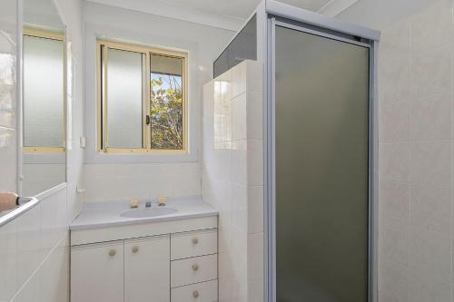 La salle de bains blanche est pourvue d'une douche et d'un lavabo. dans l'établissement Bellhaven 1, 17 Willow Street, à Crescent Head