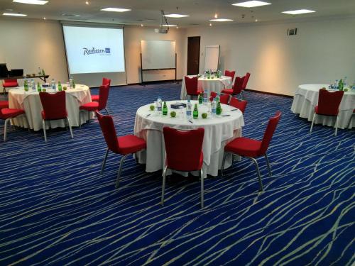 a conference room with tables and chairs and a screen at Radisson Blu Hotel, Yanbu in Yanbu