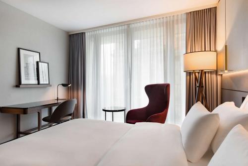 a hotel room with a large white bed and a desk at Radisson Collection Hotel, Berlin in Berlin