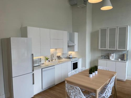 a kitchen with a table and a white refrigerator at Lou-City Penthouse Suite! Savor Life with Hollyhock in Louisville