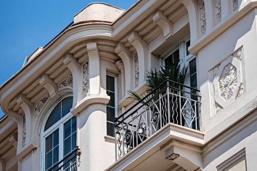 a white building with a balcony with a plant on it at Le Riviera Collection, Signature Collection by Best Western in Nice