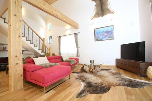 a living room with a red couch and a tv at Villa Bavaria by Hakuba White Fox Company in Hakuba