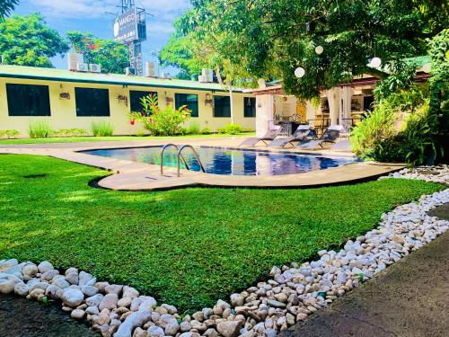 uma piscina num quintal com pedras à volta em Hotel Mango Airport em Alajuela