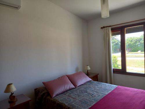 ein Schlafzimmer mit einem Bett und einem Fenster in der Unterkunft Chalecito hermoso in La Paloma
