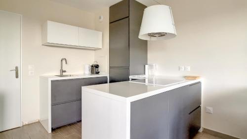 a white kitchen with a sink and a counter at T3 Riviera Apartment Near Disneyland Paris in Chessy