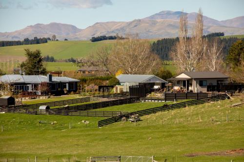 un campo con una granja con montañas en el fondo en Shearvue Farmstay with Optional Free Farm Experience at 5pm, en Fairlie