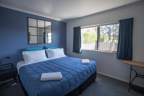 a blue bedroom with a bed and a window at Shearvue Farmstay with Optional Free Farm Experience at 5pm in Fairlie