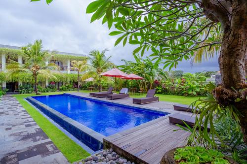 a swimming pool with a wooden deck and a resort at Puri Canggu Rooms 2 in Canggu