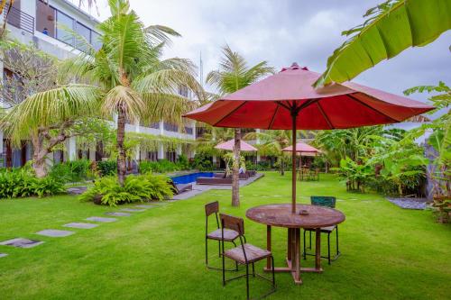 a table and chairs with an umbrella in a yard at Puri Canggu Rooms 2 in Canggu