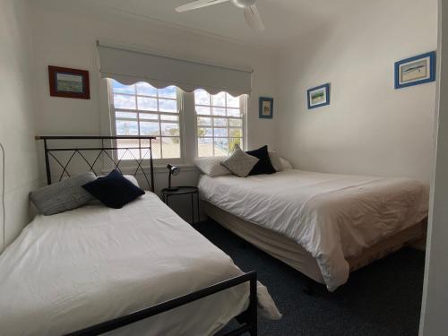 two beds in a room with a window at Allamanda House, 3 Willow Street in Crescent Head
