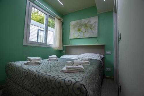 a green bedroom with a bed with towels on it at Appartamento Roero cottage 3 in Alba