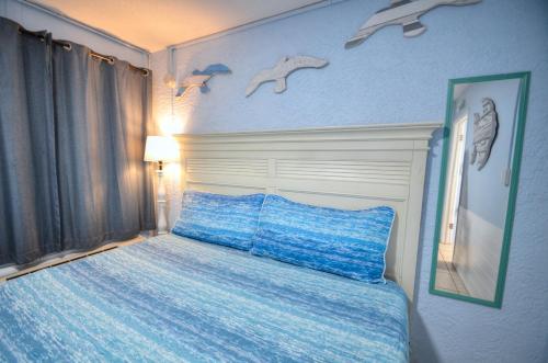 sypialnia z łóżkiem z niebieską pościelą i ptakami na ścianie w obiekcie Blue Haven Villa w mieście Panama City Beach