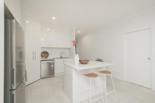 a white kitchen with a counter and two stools at Jardine Court Appartments in Rockhampton