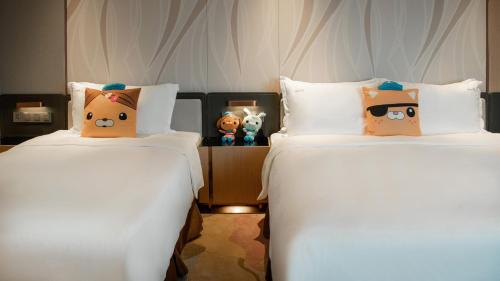two beds with hello kitty pillows in a room at Holiday Inn Luzhou Longjian by IHG in Luzhou