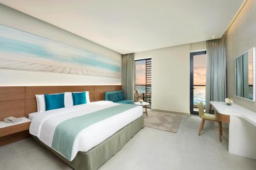 a bedroom with a large bed and a desk at Wyndham Garden Ajman Corniche in Ajman 