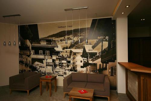a living room with two couches and a painting on the wall at Hotel Herzblut - Joker card included in summer in Saalbach Hinterglemm