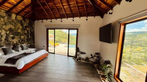 a bedroom with a bed and a large window at Hotel Campestre Palmas del Zamorano in San Gil