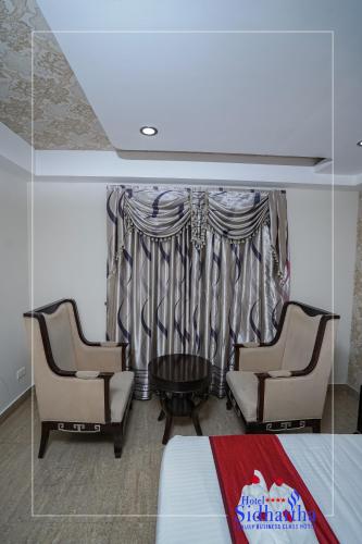 two chairs and a table in a room with a window at Hotel Sidhartha Chalakudy in Kizhake Chālakudi