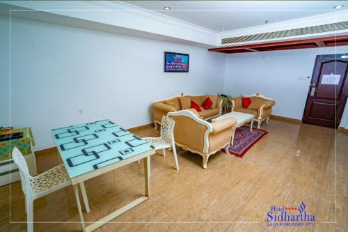 a living room with a couch and a table and chairs at Hotel Sidhartha Chalakudy in Kizhake Chālakudi