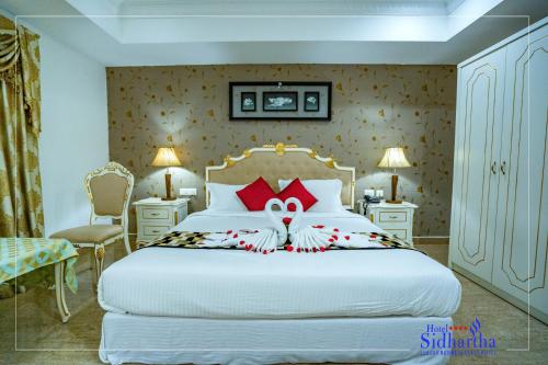 a bedroom with a large white bed with red pillows at Hotel Sidhartha Chalakudy in Kizhake Chālakudi
