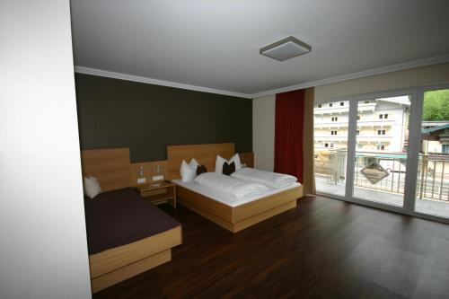 a bedroom with a bed and a large window at Hotel Herzblut - Joker card included in summer in Saalbach Hinterglemm