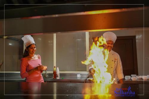 a man and a woman in a kitchen with fire at Hotel Sidhartha Chalakudy in Kizhake Chālakudi