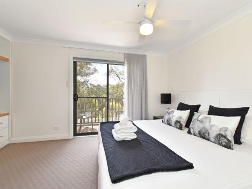 Un dormitorio blanco con una gran cama blanca y una ventana en Villa 2br Heafy Lodge Villa located within Cypress Lakes Resort, en Pokolbin